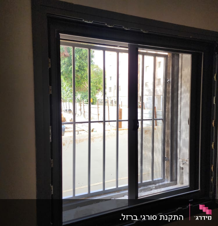 חלון עם מסגרת מתכת וסורגים חיצוניים